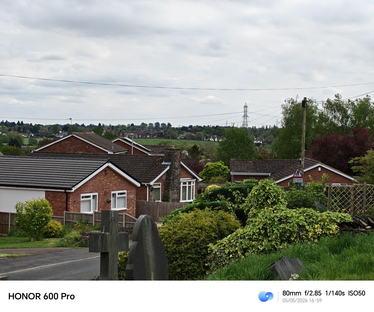 Zoomed view over rooftops, gravestones, and countryside from the Honor 600 Pro