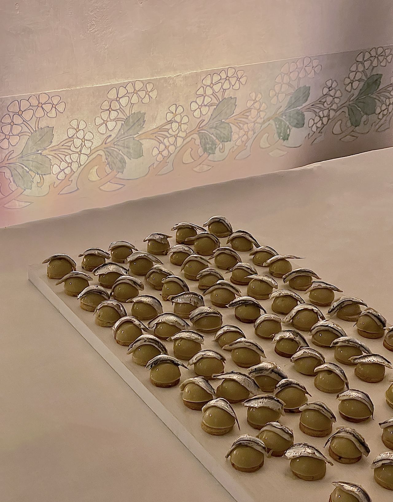 A series of food canapes sits on a table covered in a white tablecloth in an eye-catching arrangement.