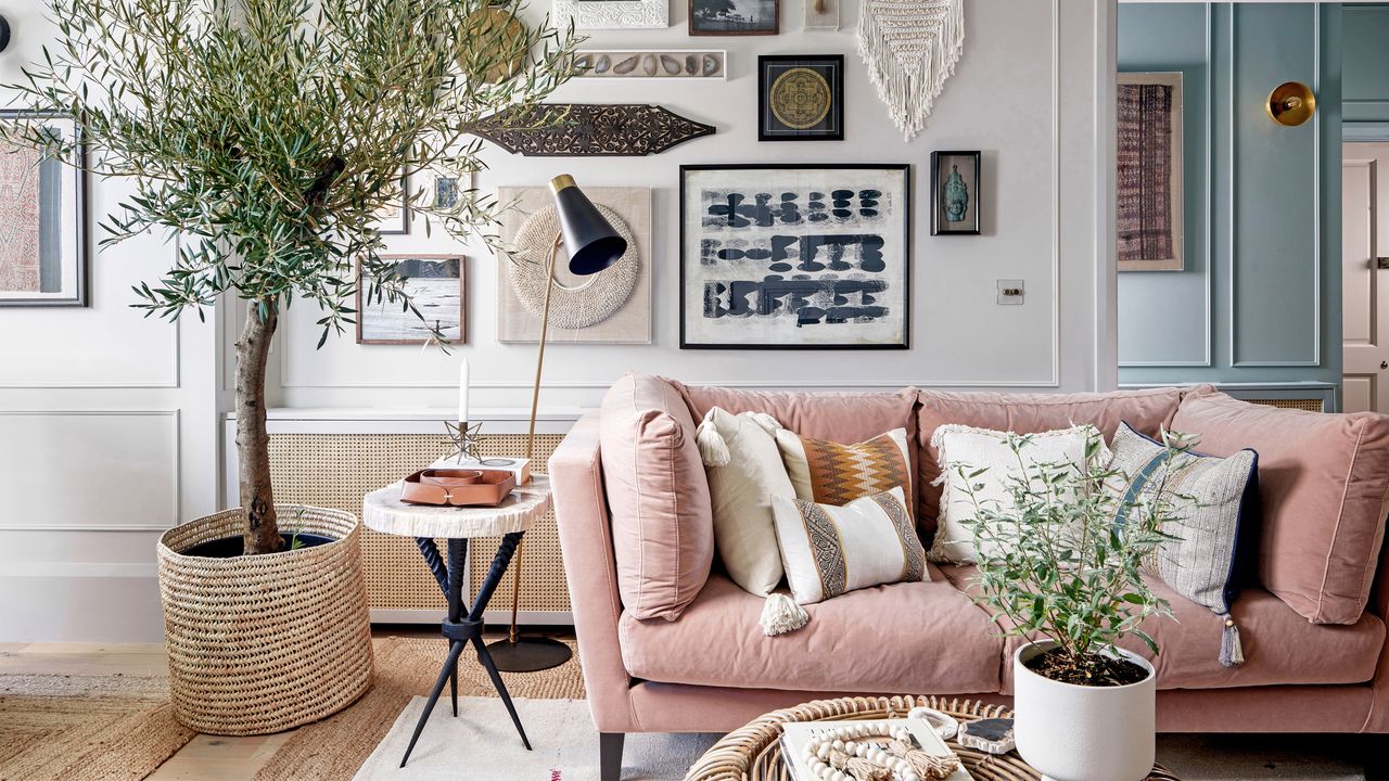 A living room with a pink sofa in front of a gallery wall