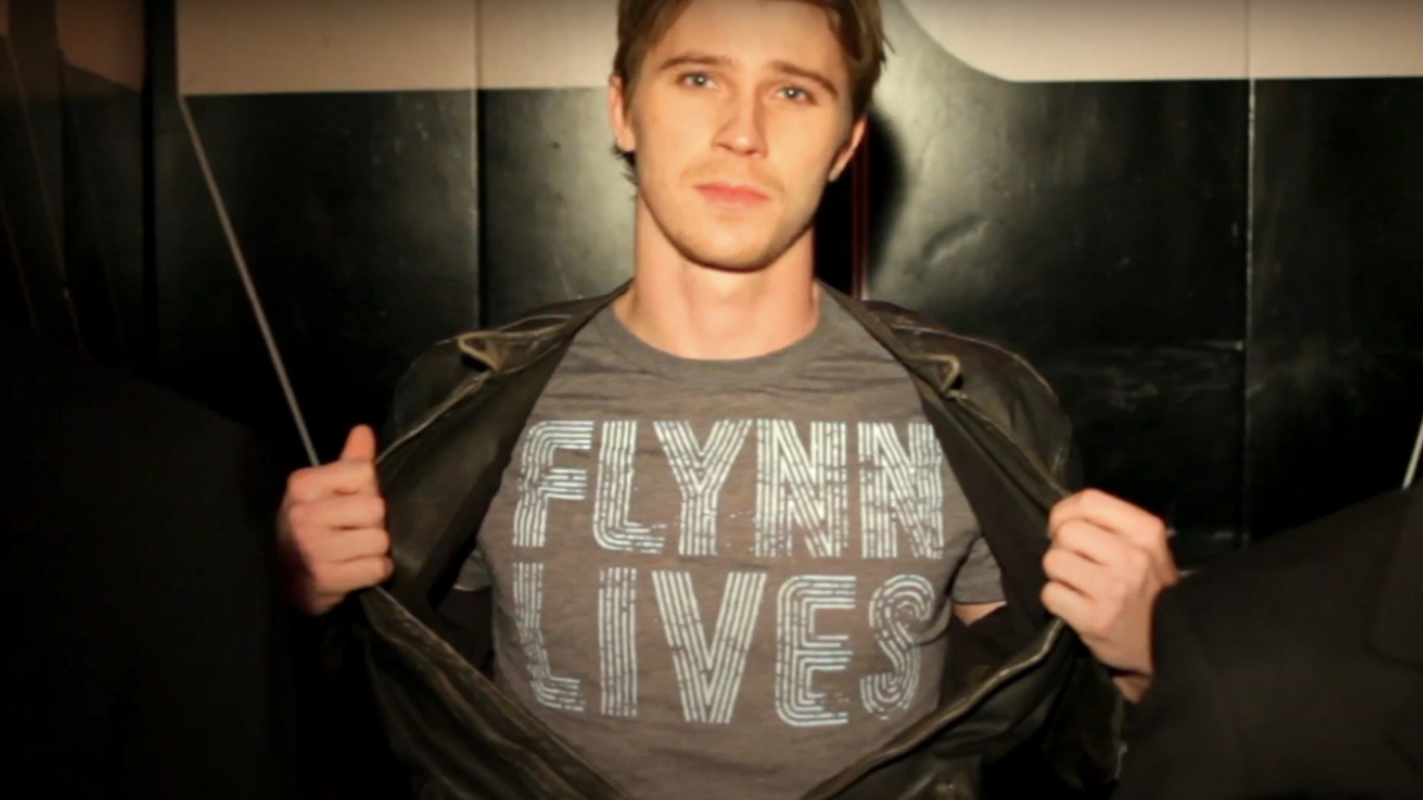 Garrett Hedlund, Tron: The Next Day'de Flynn Lives tişörtünü kameraya meydan okurcasına gösteriyor.