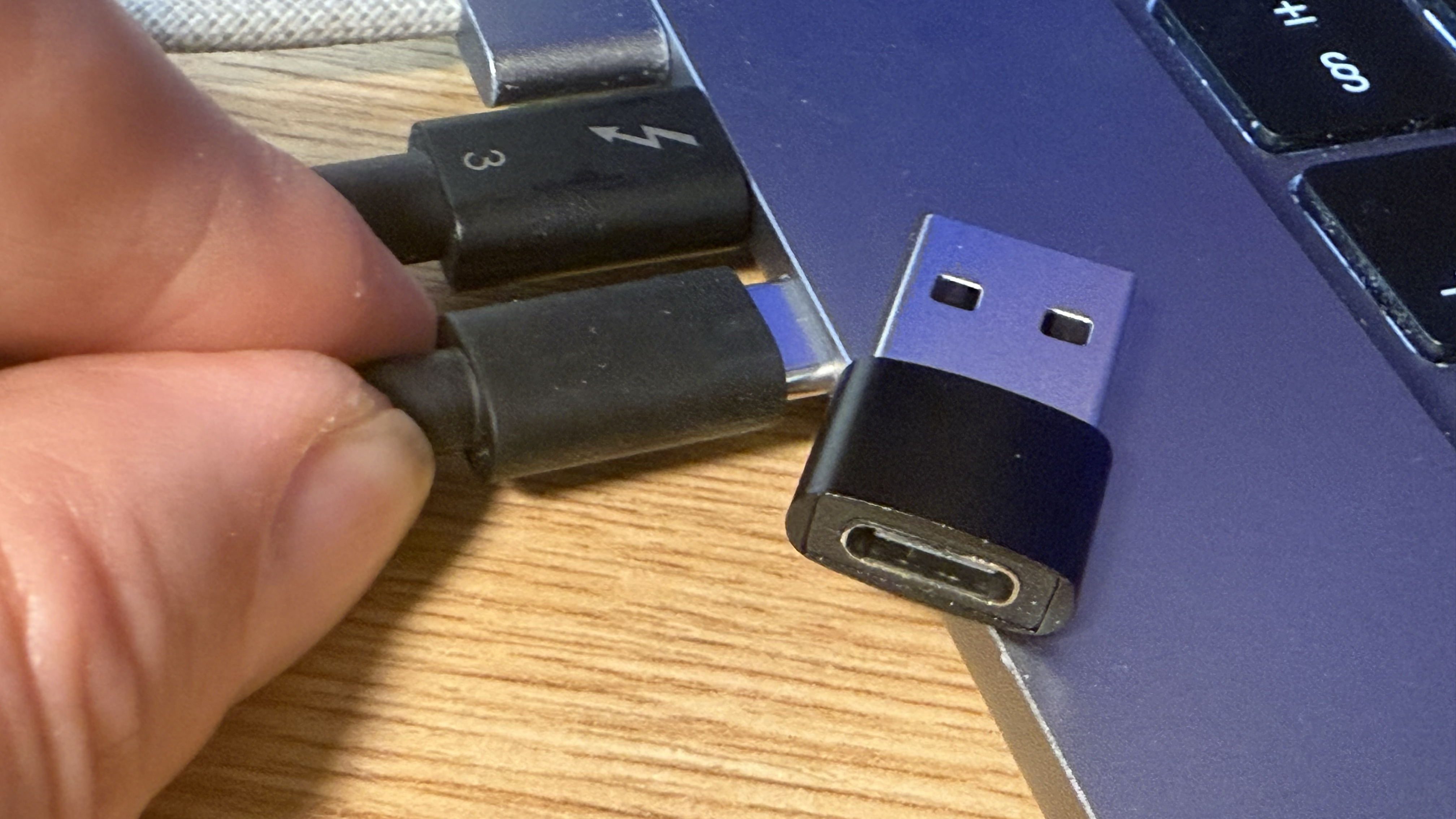 Shot of a hand plugging the webcam’s USB-C cable into a MacBook Air.