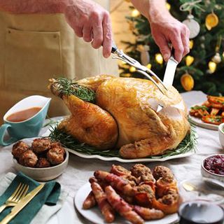 Organic KellyBronze Turkey being carved on a table with roast dinner accompaniments