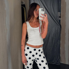 Influencer @makenna_alyse takes a mirror selfie wears a white vest top, white capri pants with black polka dots and black ballet flats.