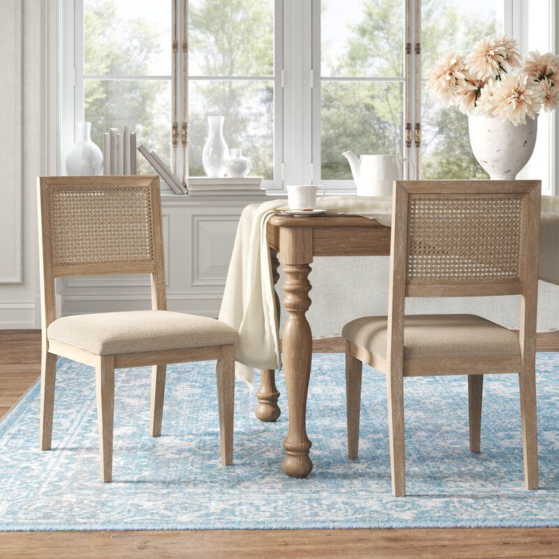 Two light wooden cane back dining chairs that