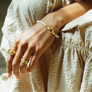 jewellery gifts woman wearing pearl bracelet with gold clasping hand detail
