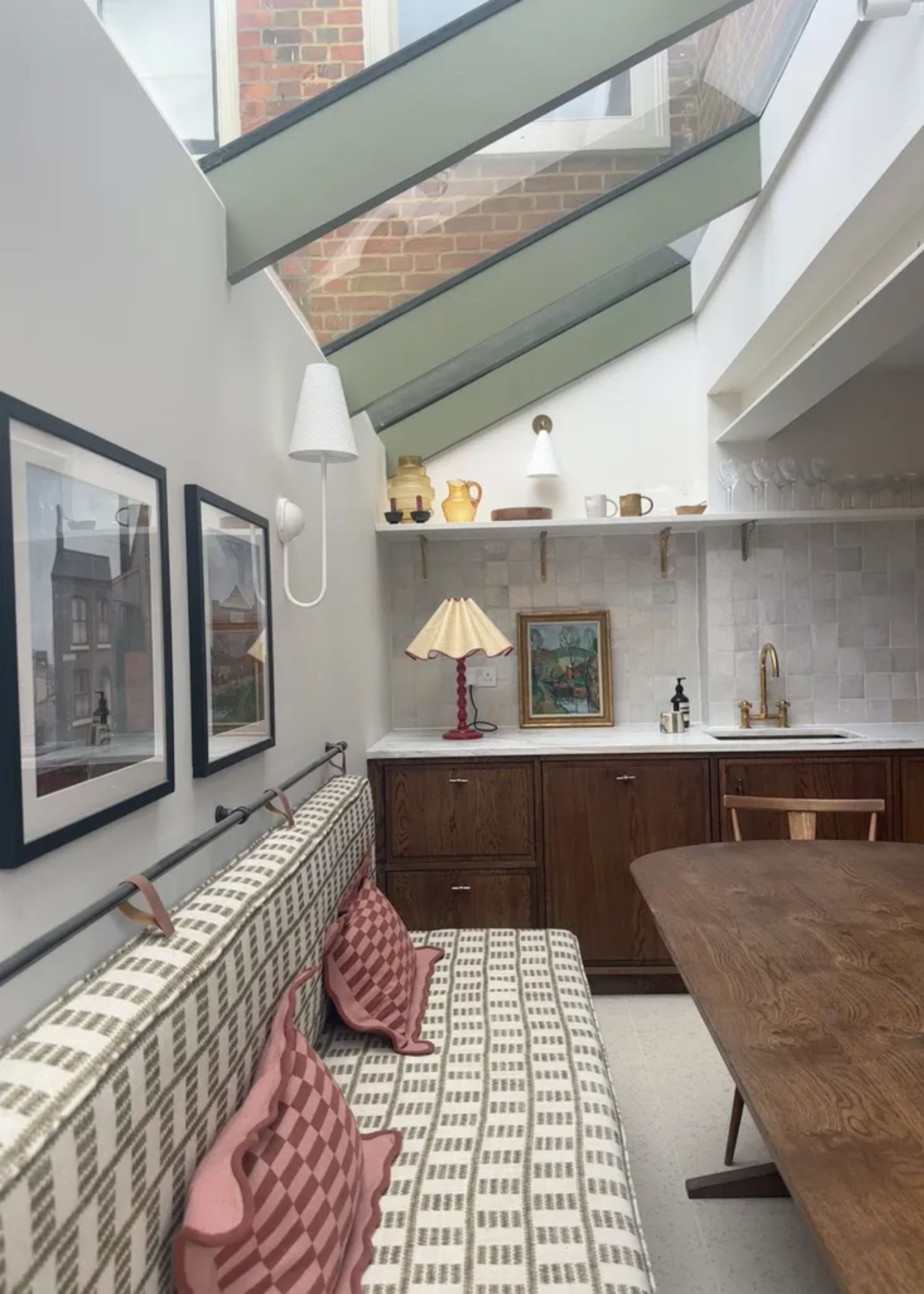 side returned extension with bench seating under a glazed skylight. a lamp sit on the countertop in the background