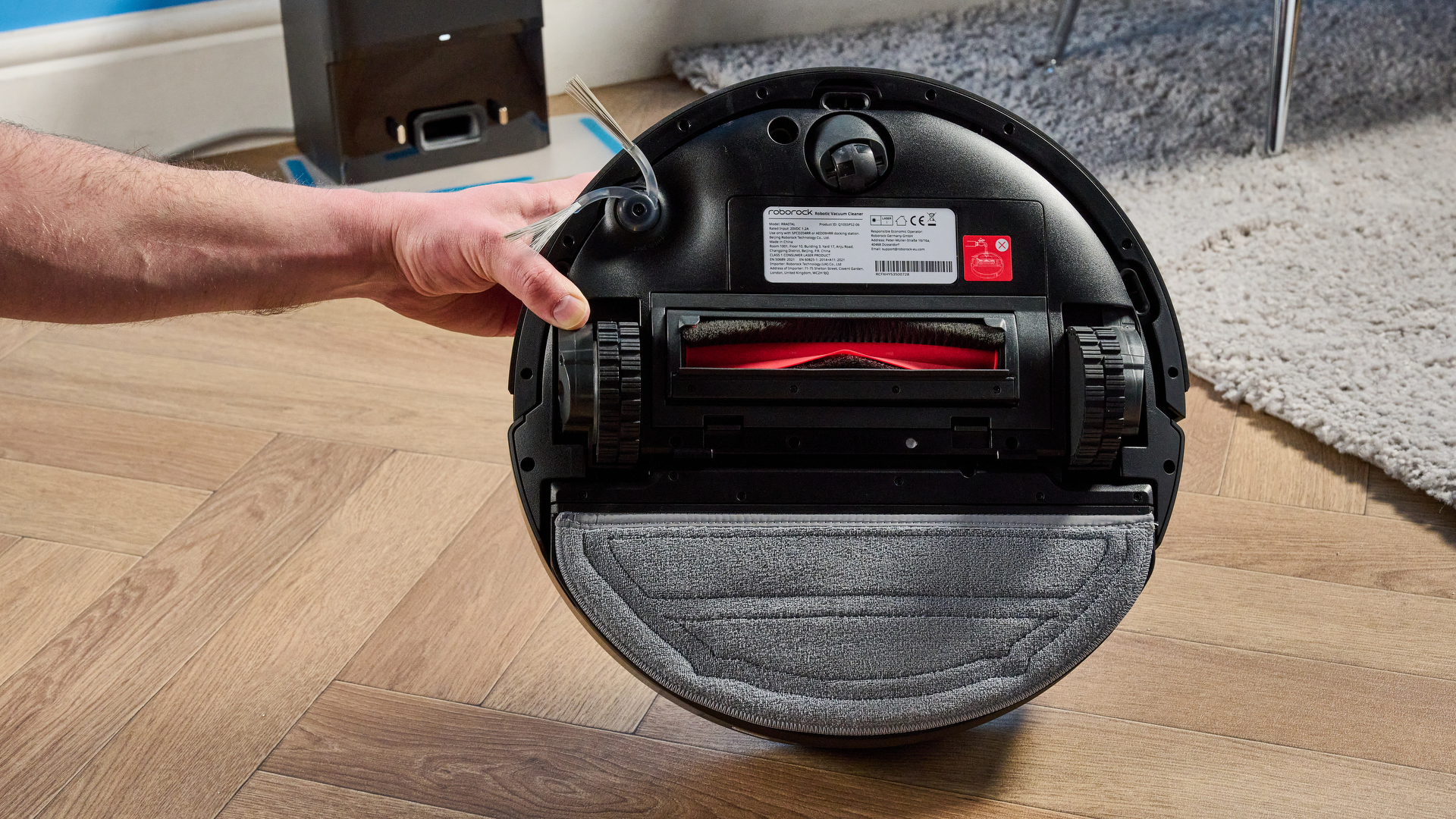 Roborock Q10 S5+ photographed on a wooden floor in front of a blue background