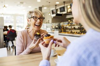 Two women in a bakery eating cakes