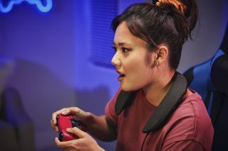 A woman enjoys playing a game while wearing the Panasonic SoundSlayer wearable speaker.