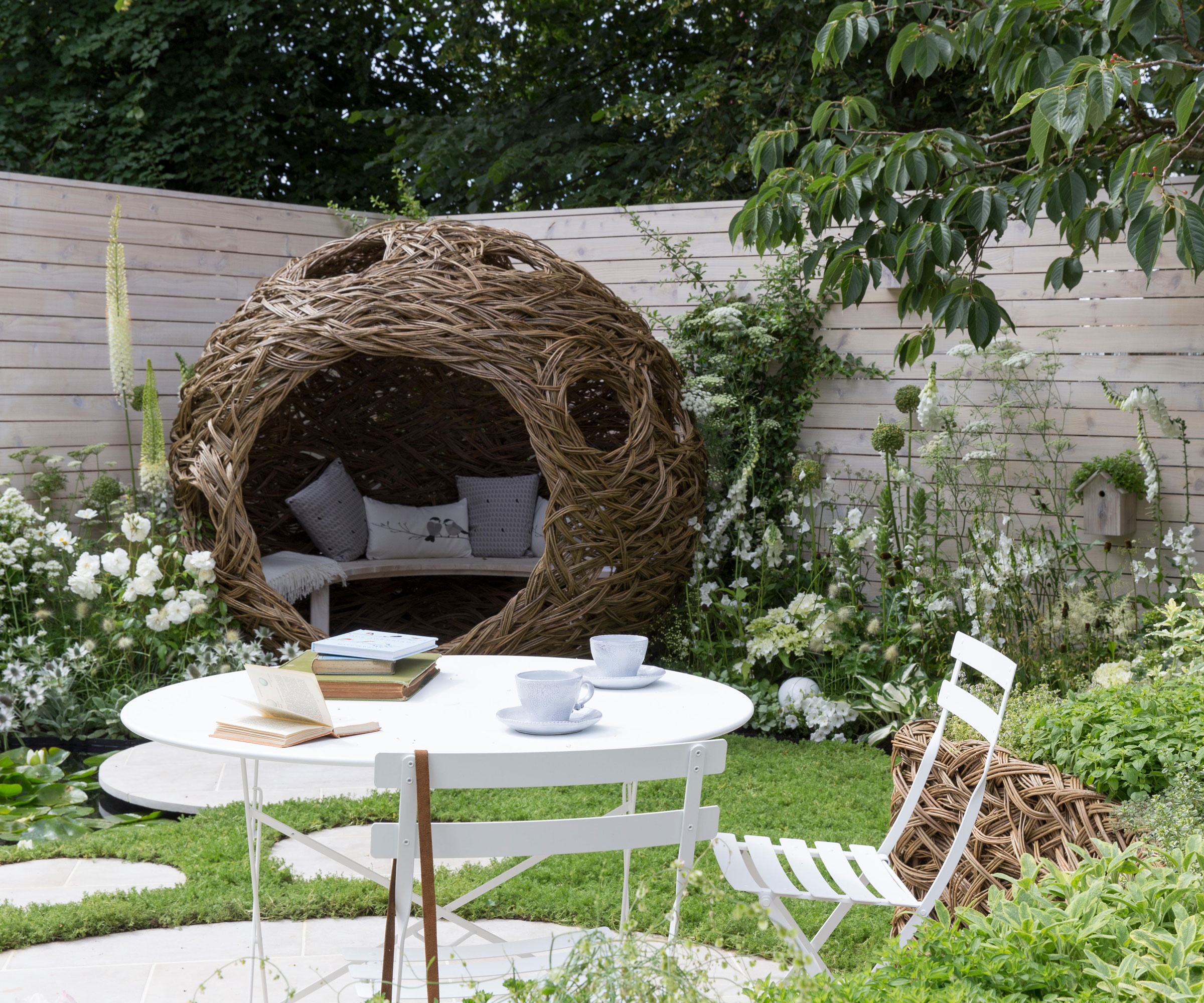 wildlife garden with willow pod, chamomile lawn, birdhouses and natural planting, with a bistro set