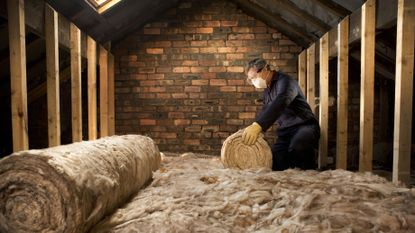 Man rolling out loft insulation