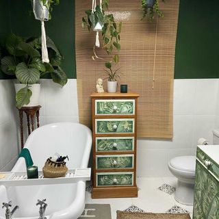 bathroom with white and green wall bathtub wooden drawer plant