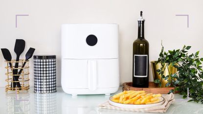 a white air fryer and other kitchen accessories, and a plate of chips on a kitchen countertop, used to illustrate an article on air fryer mistakes 