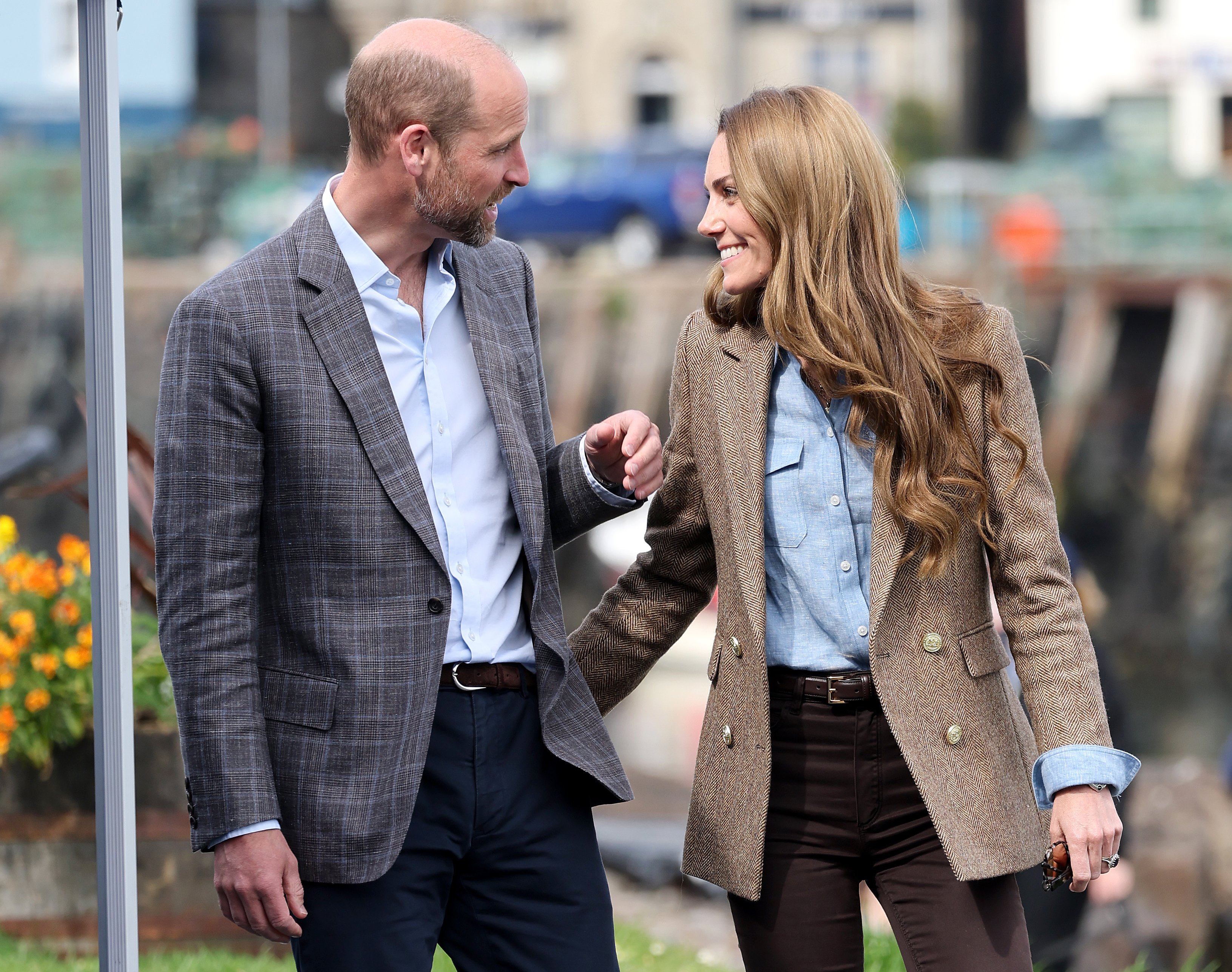 Prince William and Princess Kate smiling at each other wearing blazers