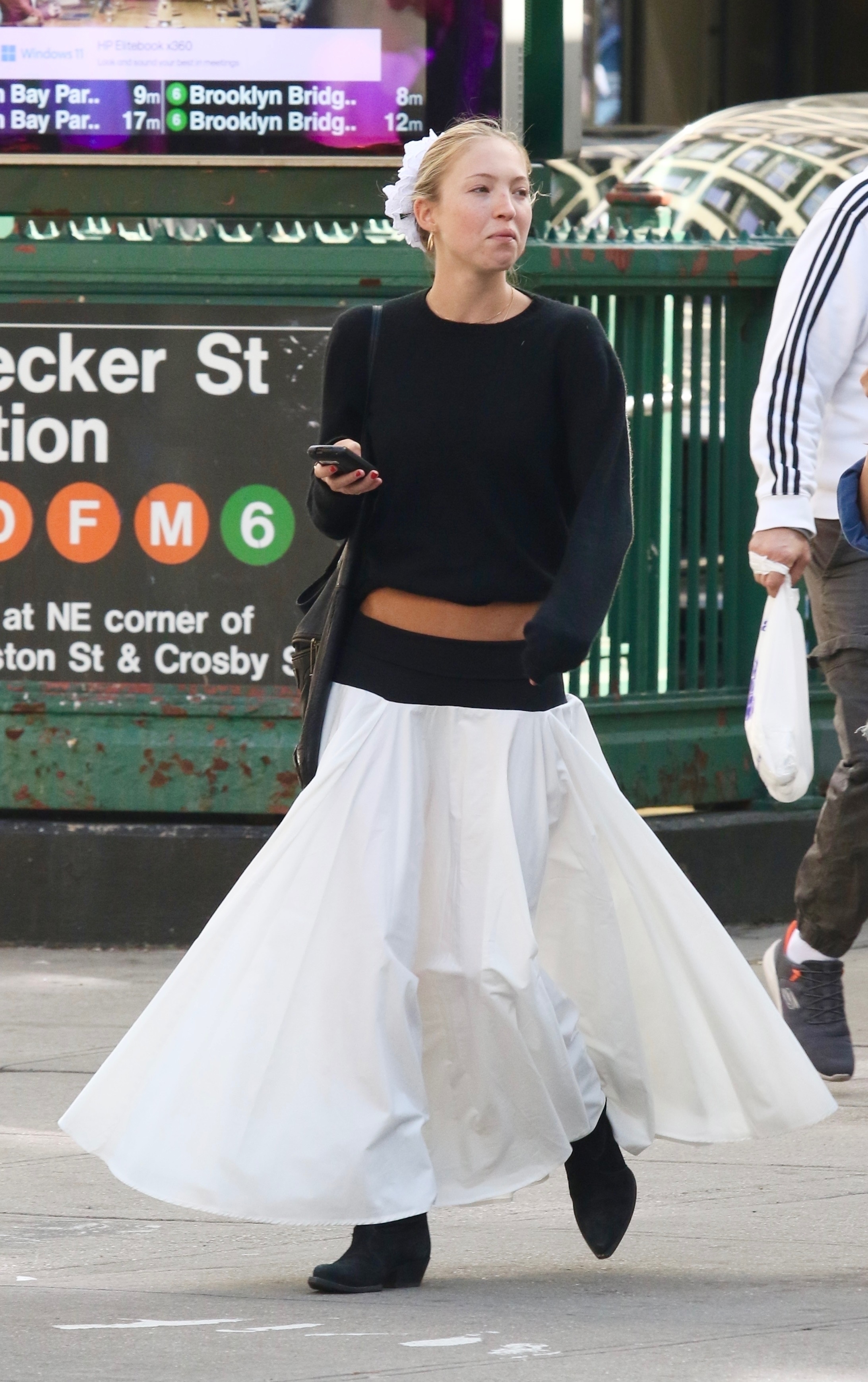 An image of Lila Moss wearing a linen skirt with black knit jumper and black boots while out in New York.