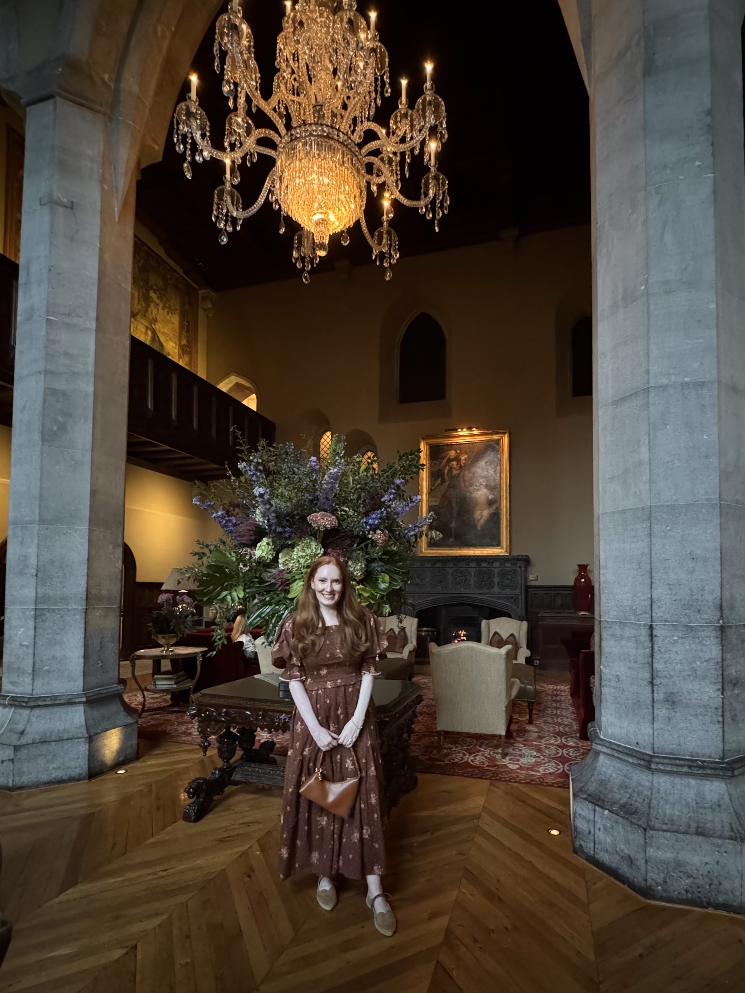 Kristin Contino wearing a brown dress standing under a chandelier