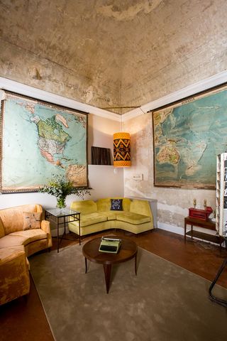 Lounge area with corner sofas, coffee table with typewriter, and old maps hanging on the walls