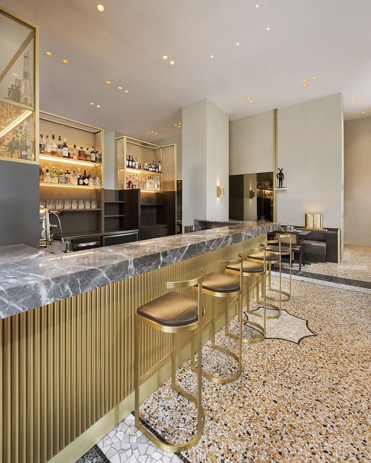 marble bar counter with gold bar stools at the Cittamani bar in Milan, Italy