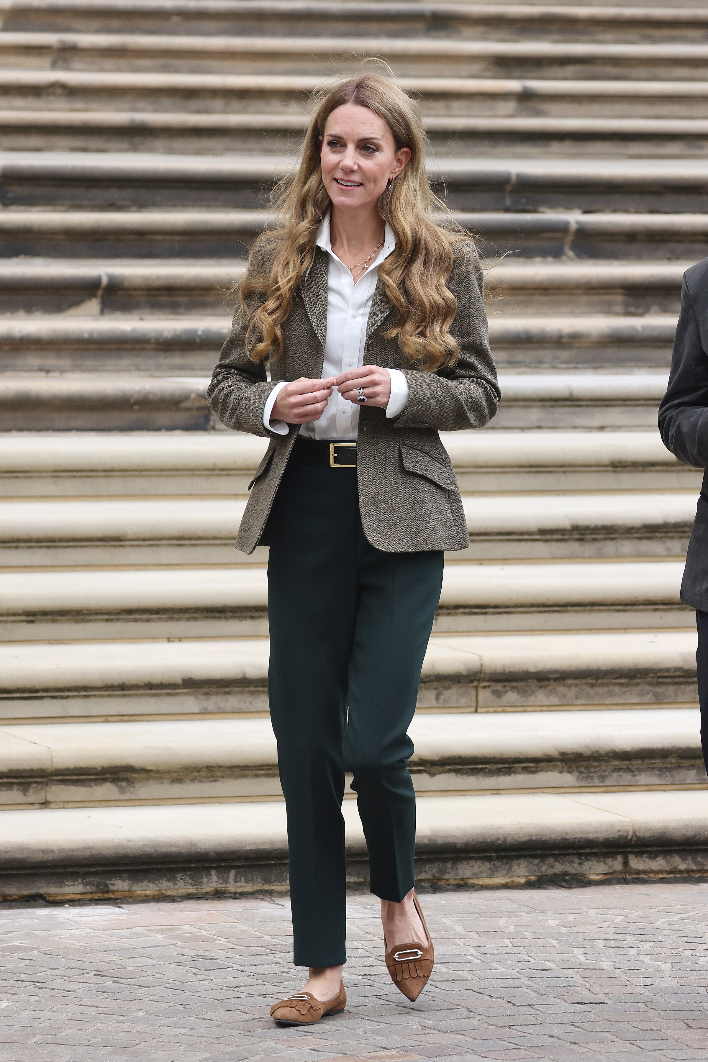 Kate Middleton wearing a blazer and pants standing in front of a staircase