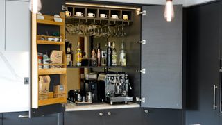 Kitchen bar area with hanging glasses and coffee machine