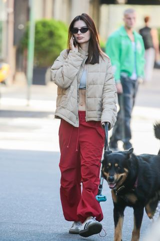 Emily Ratajkowski in New York City April 2024 wearing a sports bra, puffer jacket, and parachute pants