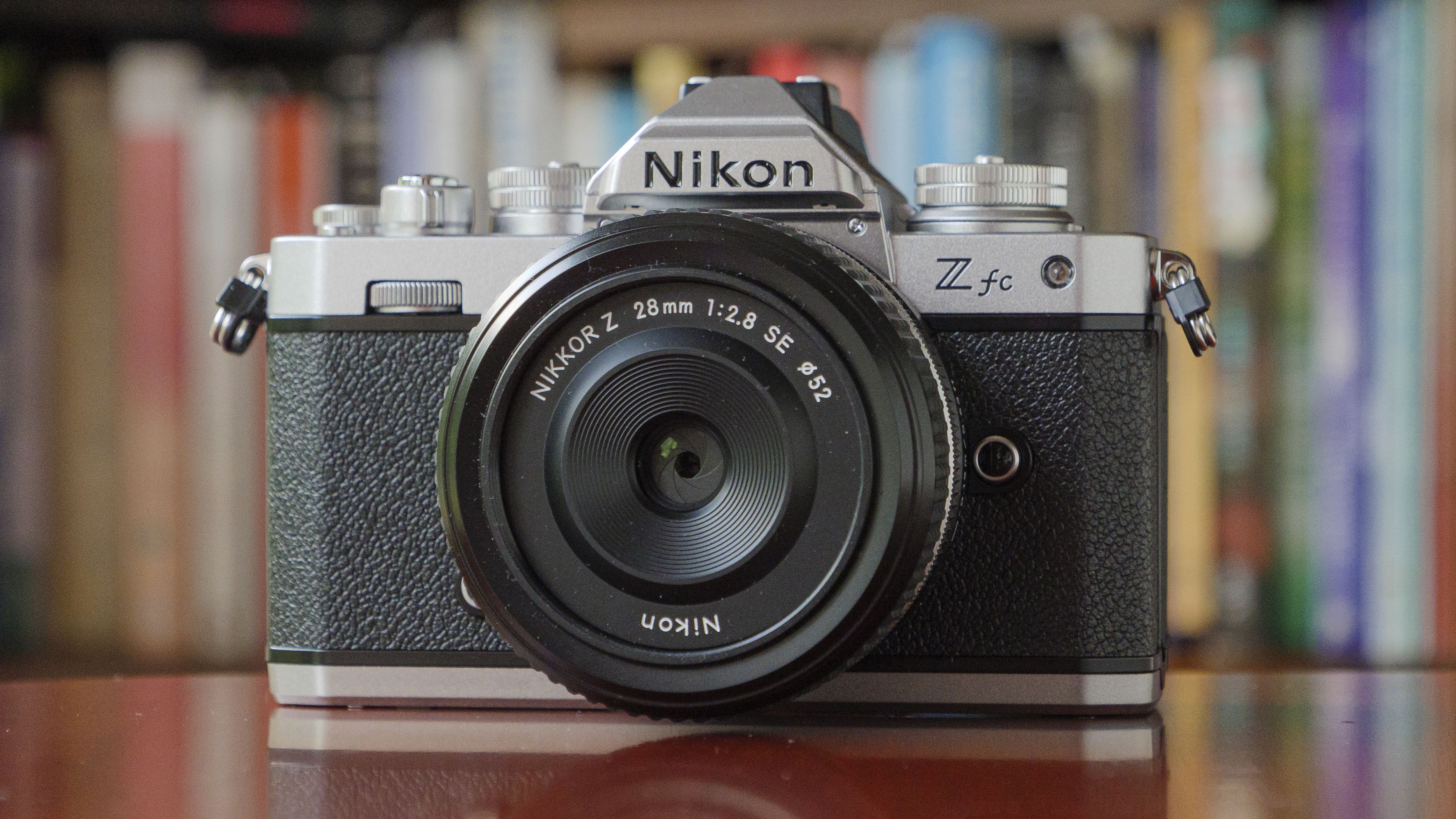 The Nikon Zfc camera sitting on a red table in front of a bookcase