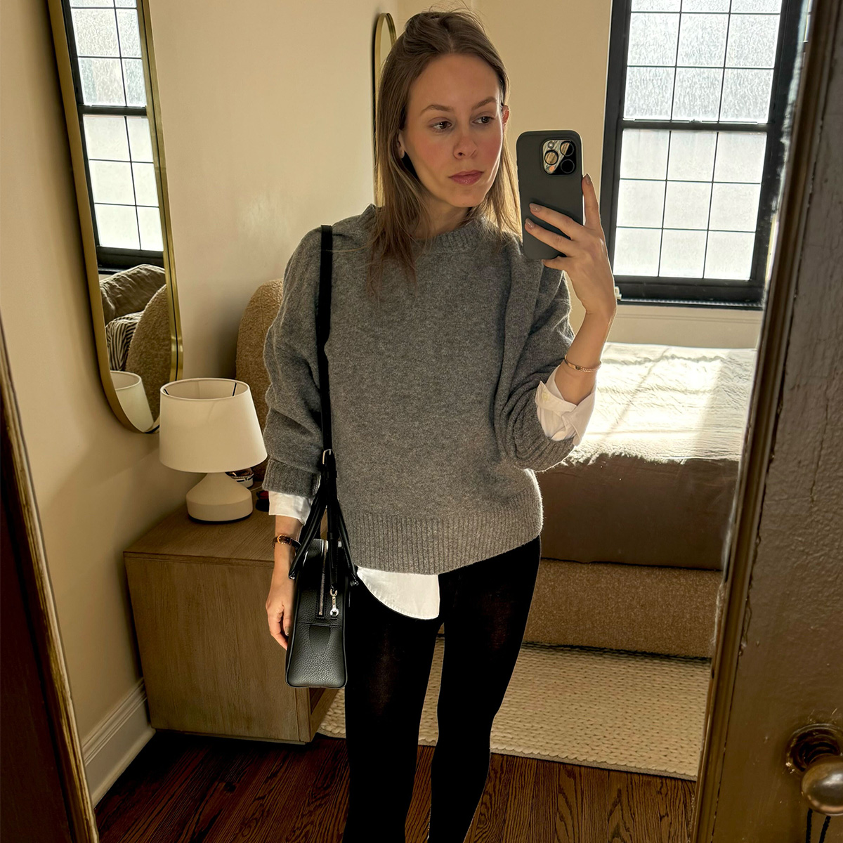 Nikki wears a black wool coat and white button-up with cashmere tights.