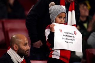 A young Arsenal fan holds up a banner