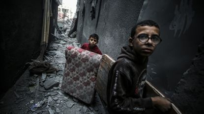 Children carry usable items after the strike on the Jabalya refugee camp in Gaza City on 1 November 2023