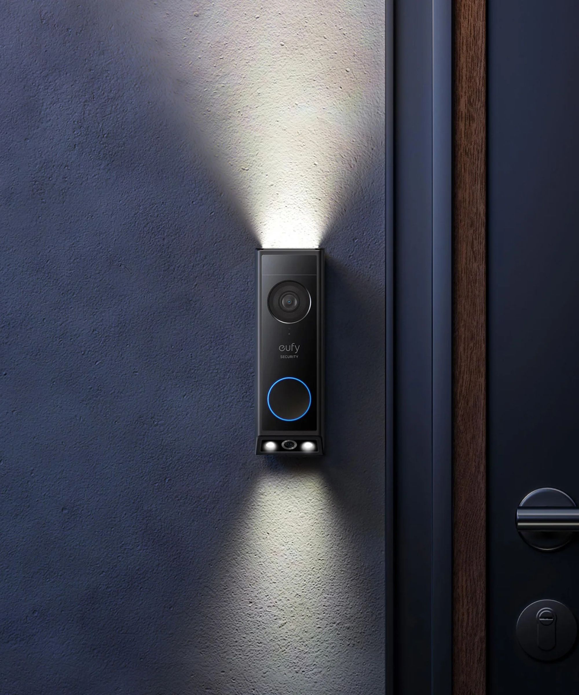 eufy E340 video doorbell, mounted on a rendered exterior wall, at night time, with built-in lights shining upwards and downward