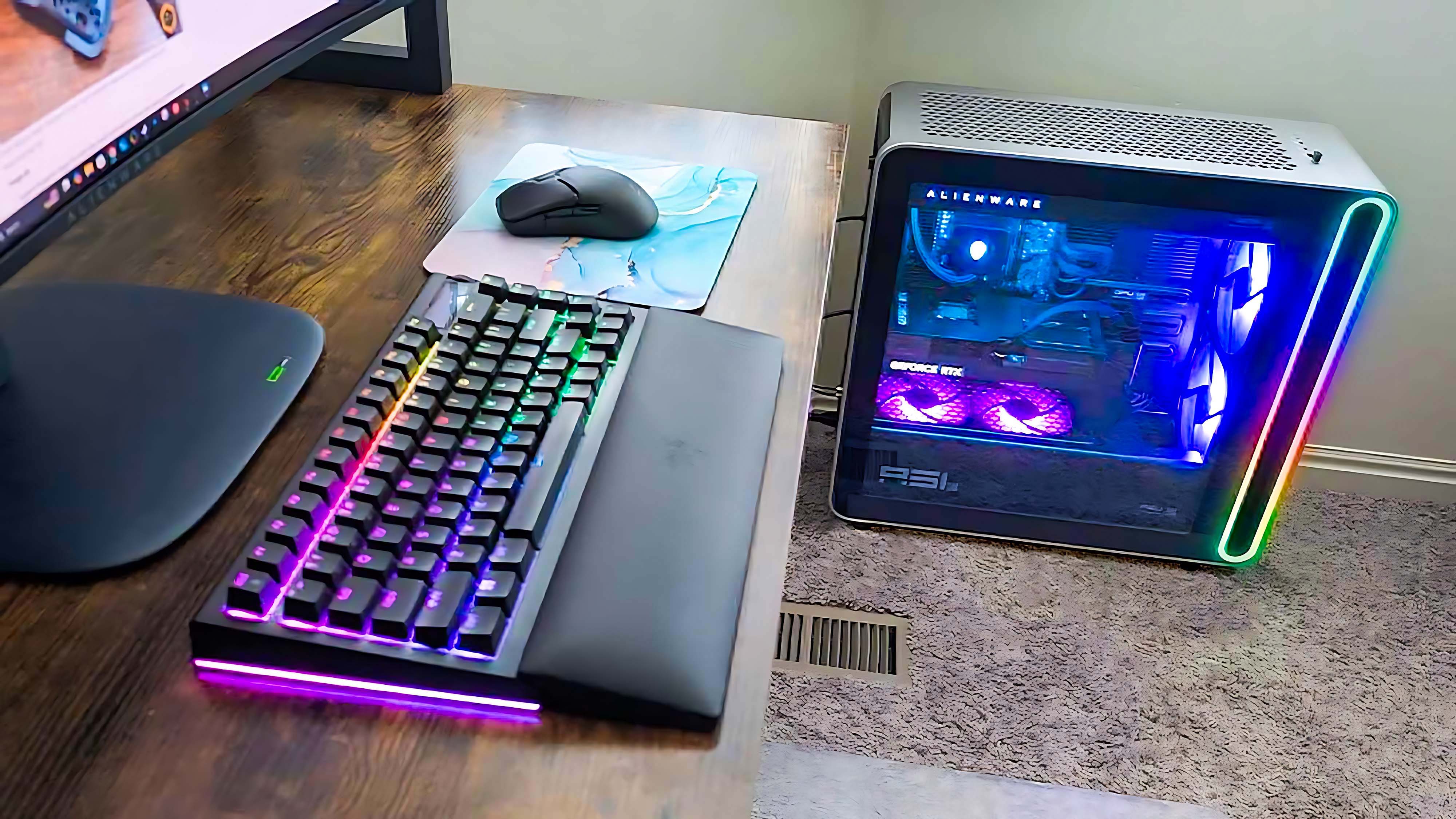 A side view of the desk that shows both an RGB keyboard and the Alienware Area-51 Gaming Desktop (2025).