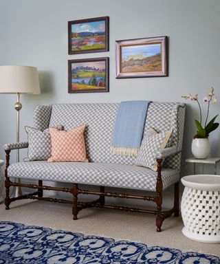 A light blue sitting room with a bench and a gallery wall
