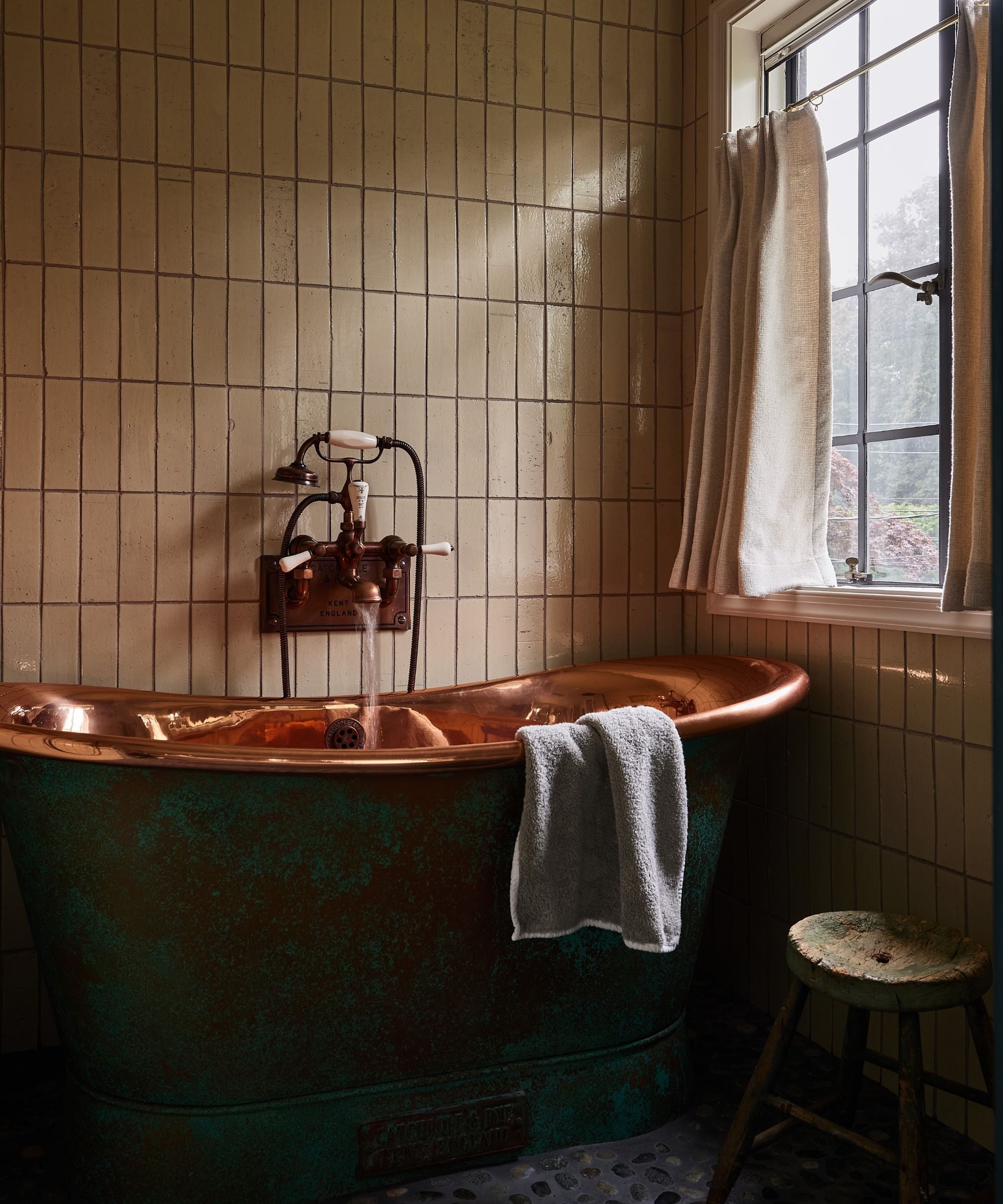 a warm primary bathrom with a copper freestanding bathtub