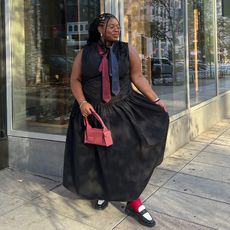 chichi wears black dress with a blue and red tie and red handbag with two toned loafers and red socks