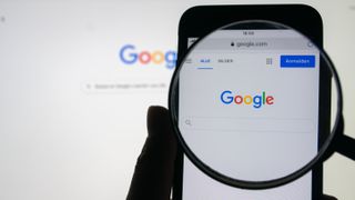 A silhouette of a person holding a magnifying glass over the Google home screen on iPhone
