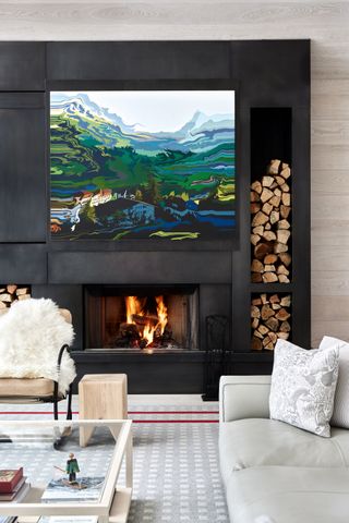 living room with fireplace with artwork hung above with gray sofa, armchair with sheepskin