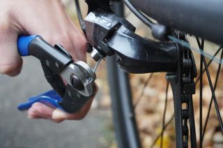 Image shows a person using cable cutters to maintain their bike on a budget.