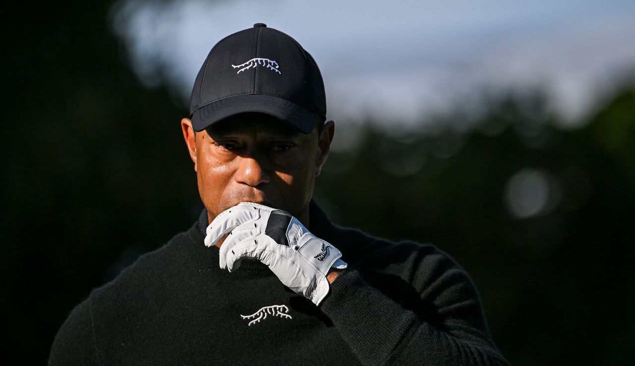 Tiger Woods walks on the fairway whilst undoing his glove