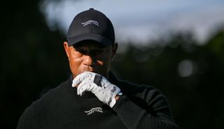 Tiger Woods walks on the fairway whilst undoing his glove