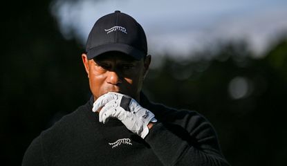 Tiger Woods walks on the fairway whilst undoing his glove