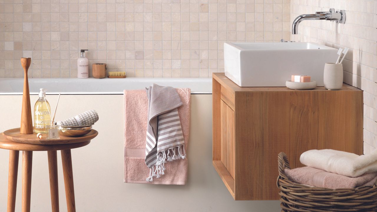 Bathroom with white built-in bath and wooden storage unit underneath sink.