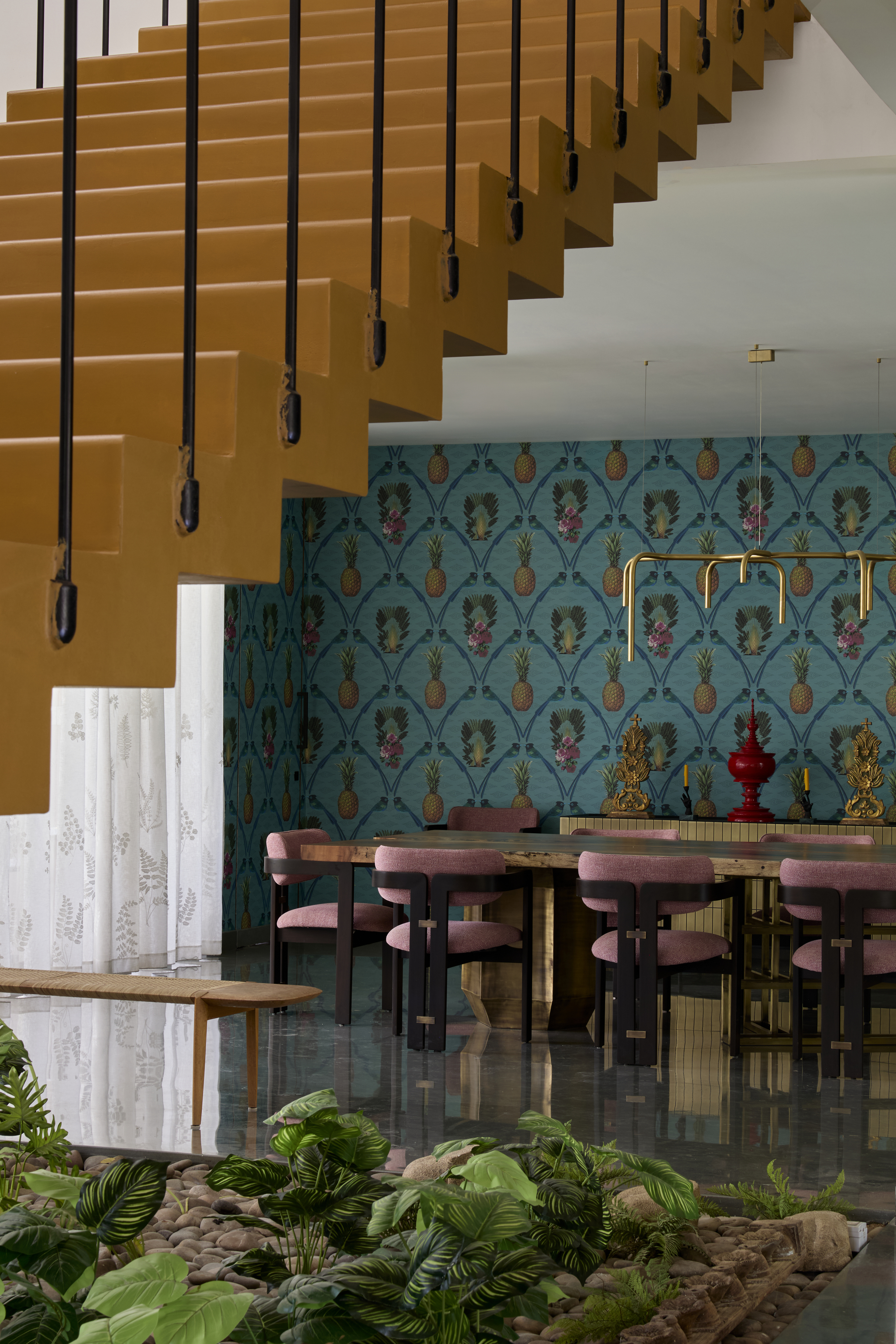 A vibrant dining room with a turquoise wallpaper, and gold chandelier