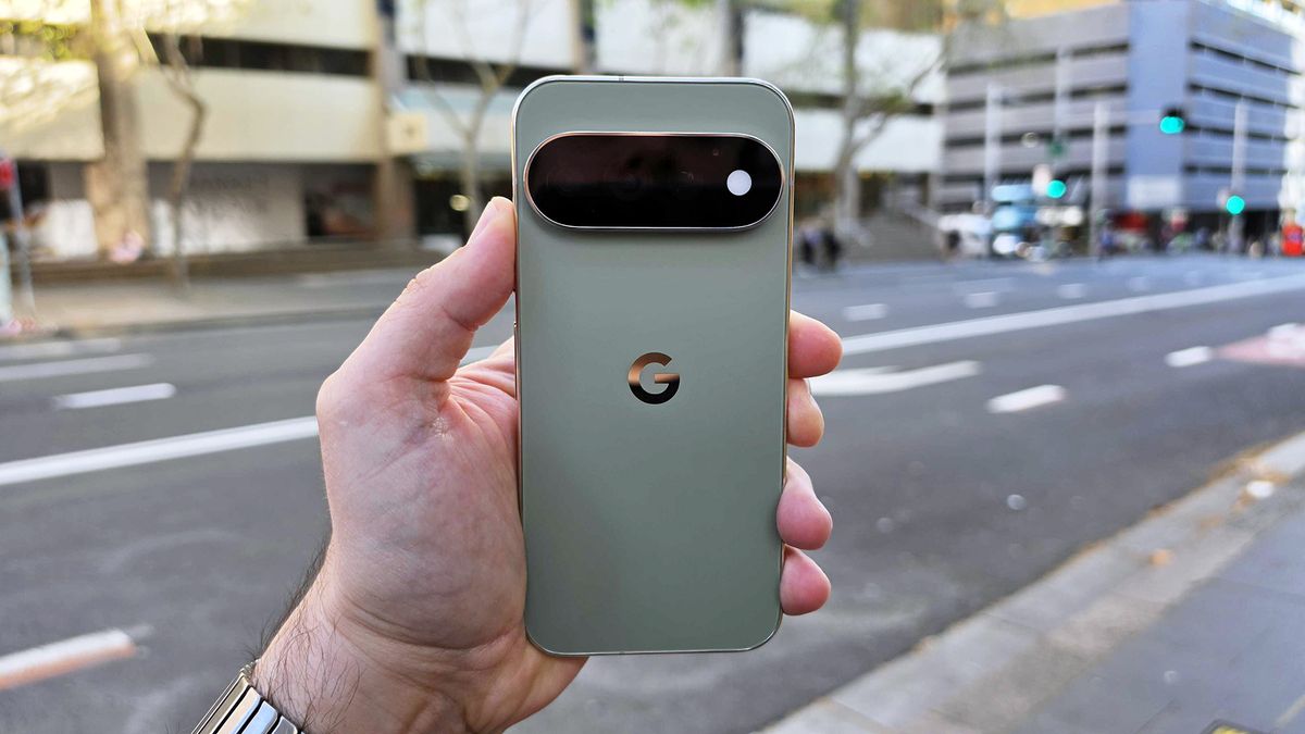 In-hand image of Google Pixel 11 Pro against street background during day time