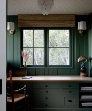 home office painted dark green with large windows