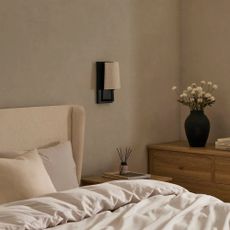 Black rechargeable lamp with linen-effect shade beside beige bed frame with wooden bedside and chest of drawers