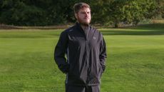 A golfer wears a Puma DRYLBL Waterproof Golf Rain Jacket