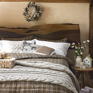 bedroom with palette of cream and brown sets the tone whilst wooden furnishings and linea chunky cable knit blanket on bed