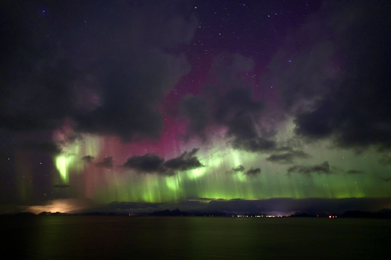 northern lights peak through behind the clouds.
