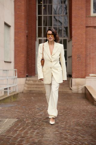 Bettina Looney wearing a yellow pinstripe suit with oversize sunglasses.