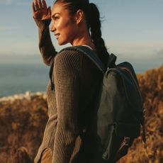 Walking workouts: A woman on a hike shielding her eyes from the sun